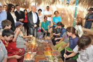 President Shimon Peres talks with Kibbutz Lotan children painting mud bricks in a workshop where children and adults foster their creativity while learning to care for the earth through the use of natural and recycled materials.